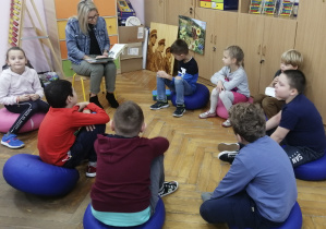 Dzieci siedzą w kręgu i słuchają czytanej poezji o tematyce jesiennej.